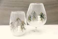 two wine glasses decorated with snowmen and pine trees