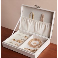 an open jewelry box on a table with bracelets, rings and necklaces in it