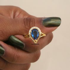 a woman's hand holding a ring with an oval shaped blue stone in it