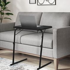 a laptop computer sitting on top of a table next to a couch in a living room