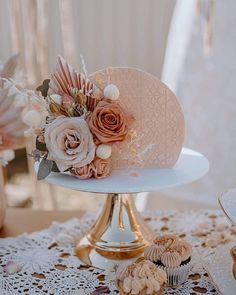 there is a wedding cake with flowers on the top and cupcakes below it