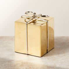 a gold gift box with two handles and a bow on the top is sitting on a marble surface