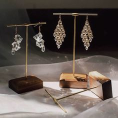 three pairs of earrings are on display in front of a wooden stand with other items