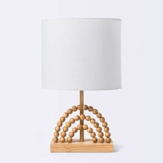 the wooden beaded table lamp is made from wood and has a white shade on top