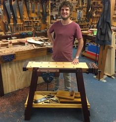 a man standing next to a workbench in a room full of woodworking tools