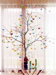 there is a tree decorated with butterflies in front of the window and curtains behind it