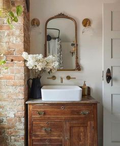 a bathroom sink sitting under a mirror next to a brick wall