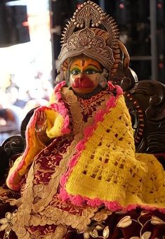 a statue of a person sitting on top of a chair wearing a costume and headdress