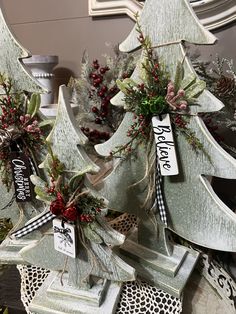 three wooden christmas trees decorated with red berries and greenery are sitting on a table