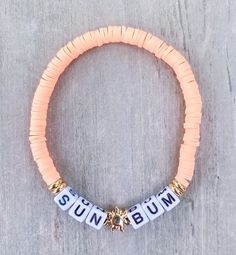 SUN BUM Bracelet ☀️🌴 This bracelet is for the lover of the sun, with a drink in her hand and her feet in the sand ☀️☀️ Made with peach mini heishi beads, 18k gold filled accents and mini square letters that read "SUN BUM" If you would like another word or color, please put in Personalization Section* CARING TIPS FOR YOUR JEWELRY ⭐️Treat and store with care. ⭐️ For longevity, avoid exposing your jewelry to water. ⭐️ Avoid having direct contact with lotions, perfumes, sanitizers as these chemical Beach Bracelet With Letter Beads, Adjustable Stretch Bracelet With Letter Beads For Vacation, Adjustable Letter Beads Stretch Bracelet For Vacation, Adjustable Gold Stretch Bracelet For Vacation, Personalized Gold Friendship Bracelets For Beach, Adjustable Strand Bracelets With Letter Beads, Adjustable Gold Beaded Bracelets For Beach Season, Summer Gold Bracelets With Letter Beads, Personalized Bohemian Friendship Bracelets For Beach