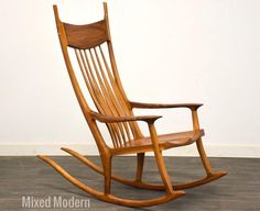 a wooden rocking chair sitting on top of a hard wood floor next to a white wall