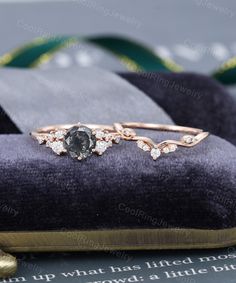 an engagement ring with diamonds on top of a velvet cushion in front of a book