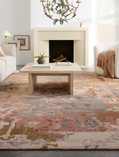 a living room with a couch, coffee table and fire place in the middle of it