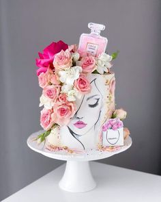 a white cake with pink flowers and perfume bottle on top, sitting on a table