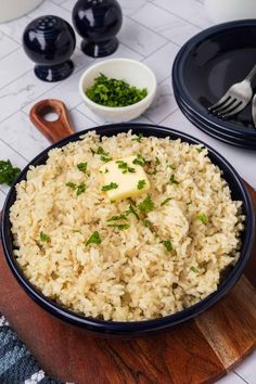 a bowl filled with rice and topped with butter on top of a wooden cutting board