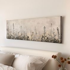 a painting hanging on the wall above a bed with pillows and pillow cases in front of it