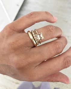 a woman's hand with a gold ring and an engagement ring on her finger