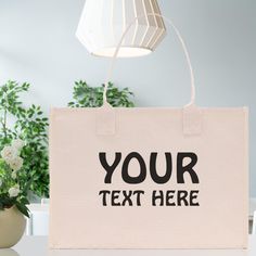 a canvas bag sitting on top of a table next to a lamp and potted plant