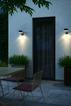 two chairs sitting on top of a patio next to a table and potted plants