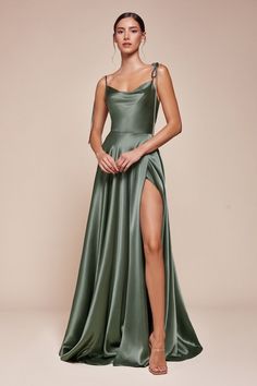 A woman stands confidently in a flowing green satin dress with a high slit, showcasing her leg. The backdrop is a soft beige, enhancing the elegance of the outfit. Silky Dresses Long, Bridesmaid Dress Styles Satin, Green Elegant Dresses, Silky Dress Long, Bridesmaid Dress Satin, Romantic Gown, Simple Satin, Cinderella Divine, Shirt Jacket Men