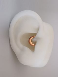 an ear with a gold ring is shown against a white wall and it looks like something out of space