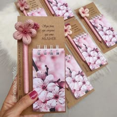 a hand holding a notebook with pink flowers on it, and four notepads attached to the cover