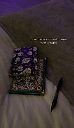 two notebooks sitting on top of a bed with a pen next to it and the words your reminder to write down your thoughts