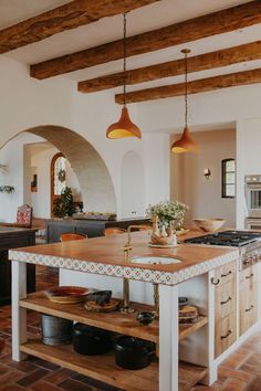 a large kitchen with an island in the middle of it and wooden beams on the ceiling