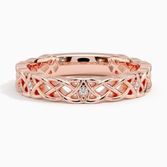 a rose gold wedding band with diamonds on the sides and an intricate design in the middle