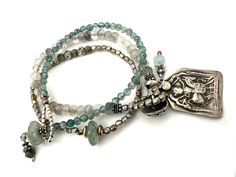 Handmade Boho Bracelets featuring a Vintage Hindu Durga Warrior Goddess Silver Charm (about 1 1/2" x 7/8") pairs with small faceted Gray and Cloudy Quartz beads.  There is a 925 Sterling Silver Embossed Button that serves as the clasp, added to the set is a small Aqua glass beaded bracelet with an Aventurine Bead clasp.  Last is small silver tone beads with coordinating Aqua colored beads.  The set is charming, unique and perfect for the Warrior Woman in us all. Specifics ✥ Small Green Bracele 7.5"   ✥ Gray Quartz Bracelet 7.75" ✥ Silver Stretch Bracelet 6.25" Inner Diameter ✥ Includes Gift Packaging In a world of mass production, Kálon Style specializes in meticulously designed, exquisite jewelry and home decor you can be assured are as rare and beautiful as you!  There is a large variety Nickel Free Silver Bohemian Wrap Bracelet, Nickel-free Silver Bohemian Wrap Bracelet, Bohemian Silver Wrap Bracelet, Nickel Free, Silver Bohemian Wrap Bracelet Nickel Free, Bohemian Nickel-free Silver Wrap Bracelet, Silver Gemstone Beads Amulet Jewelry, Silver Amulet Jewelry With Gemstone Beads, Bohemian Sterling Silver Bracelets With Polished Beads, Silver Hand-strung Bracelets As Gifts