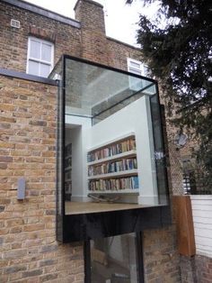 a brick building with a large glass window on the outside and bookshelves in front