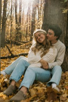 a man and woman sitting next to each other in the leaves