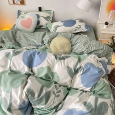 an unmade bed with blue and green comforter on it in a bedroom next to a lamp