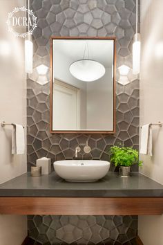 a bathroom with a sink, mirror and lights on the wall above it's counter