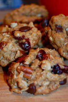 several cookies with nuts and cranberries on a wooden table next to a red cup