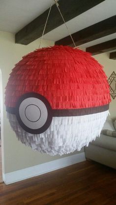 a red and white ball hanging from a ceiling in a living room with wood flooring