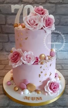 a pink and gold birthday cake with flowers on top