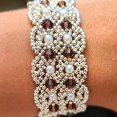 a close up of a person's arm wearing a bracelet with pearls and beads