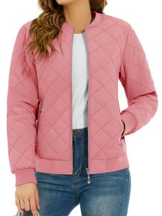 a woman wearing a pink quilted jacket and white t - shirt with her hands in her pockets