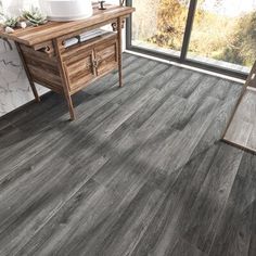 a bathroom with grey wood flooring next to a large window