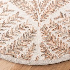 a white rug with brown leaves on the top and bottom, in front of a wooden floor