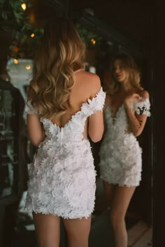 the back of a woman's dress in front of a mirror with her reflection