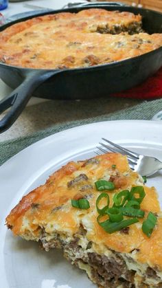 a white plate topped with a slice of quiche next to a skillet filled with meat and cheese