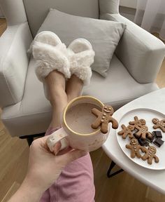 a woman holding a cup with some cookies on it and her feet in the mug