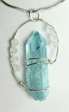 a necklace with a large piece of blue glass and silver wire hanging from it's center