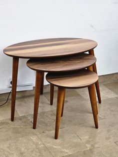 three wooden tables stacked on top of each other in the middle of a floored room