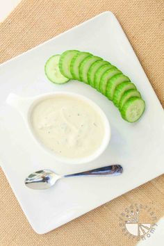 a white plate topped with cucumber slices next to a bowl of ranch dressing