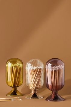 three different colored vases with matches in them