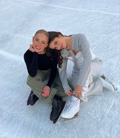 two young women sitting on the ice with their arms around each other