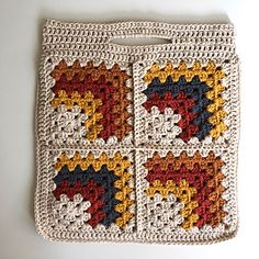 a crocheted granny blanket with two squares on it and some yarn next to it